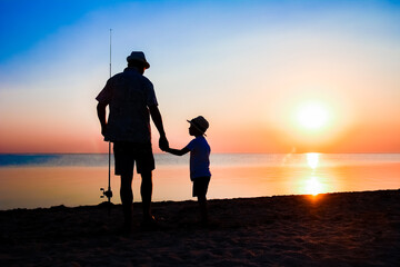 A Happy father and child fishermen catch fish by the sea on nature silhouette travel