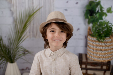 Boy wearing a hat making faces with a brick wall and neutral clothes 