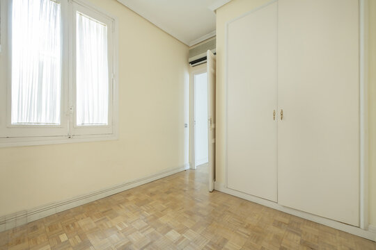 living room of an empty house with light walls, paruqet floors and built-in cabinets with white sliding doors