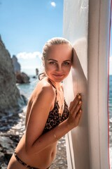 Woman in black bikini sap sea. Portrait of a happy girl on the background of a surfboard in the sea on a sunny summer day