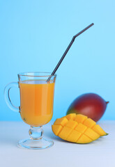 Mango juice in a glass with a straw on a blue background. Selective focus.