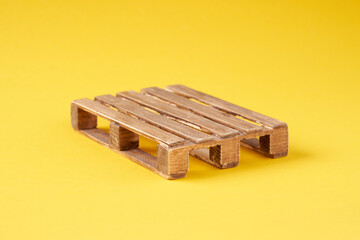 A wooden transport pallet on a yellow background.