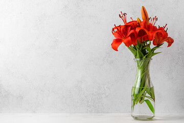 Orange lily flowers bouquet in vase on white background. Still life. Wedding or Mothers day card with copy space