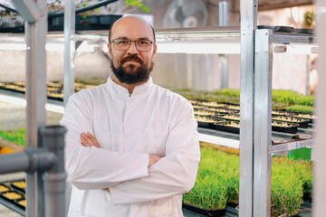 portrait of smiling male gardener in glasses and white coat at microgreen farm Healthy vegan food Organic plant germination