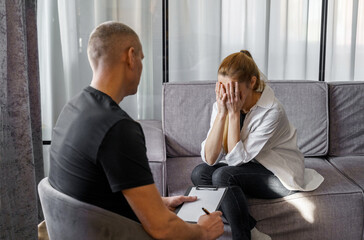 A male psychologist consults a female patient, makes notes.