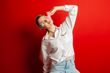 Portrait of a lovely tender girl wearing a feather decorations and posing. Isolated on a red background.