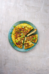Traditionelle italienische Gemüse Frittata mit Zucchini, Zwiebel und Käse serviert als Draufsicht auf einem Nordic Design Teller mit Textfreiraum 