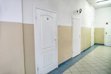 Corridor with white walls, white plastic doors and communications.
