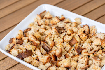 Crispy cubes of bread, croutons of white bread for cream soups. crackers on a white plate of wheat bread with olive oil and garlic. Recycling zero waste concept