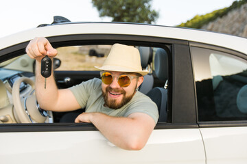 Naklejka premium Handsome happy man showing key of new car - Rental and buy new car concept