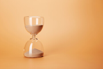 Hourglass with clean sand pouring down countdown the time, isolated on the bright solid fond plain...