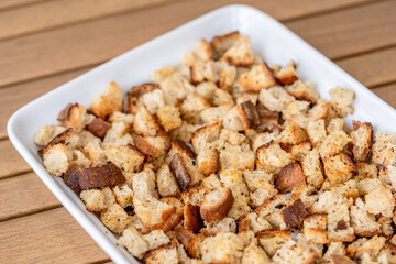 Crispy cubes of bread, croutons of white bread for cream soups. crackers on a white plate of wheat bread with olive oil and garlic. Recycling zero waste concept