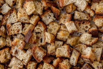 Crispy cubes of bread, croutons of white bread for cream soups. Food texture background of sourdough wheat bread with olive oil and garlic. Recycling zero waste concept