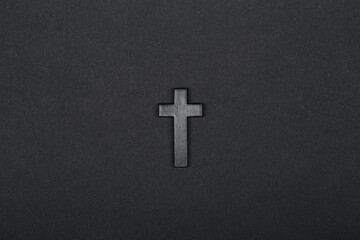 Black wooden cross isolated on the solid fond plain black paper background