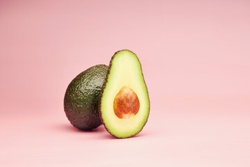 Avocado slice with the pit isolated on the bright solid fond plain pink background