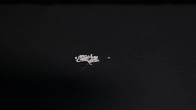 Potassium sorbate, potassium salt of sorbic acid. Chemical oblong pellets fall on dark surface. Antimicrobial industrial ingredient increase shelf life products. Food additive E202.