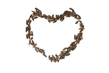Sunflower seeds in the shape of a heart on white background.