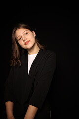 portrait of a beautiful young brunette woman in a black blouse on a black background. strict portrait of a girl on a black background