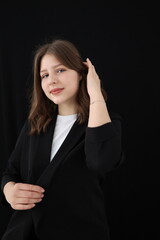 portrait of a beautiful young brunette woman in a black blouse on a black background. strict portrait of a girl on a black background