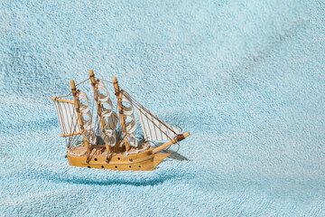 A wooden sailboat on a blue towel.