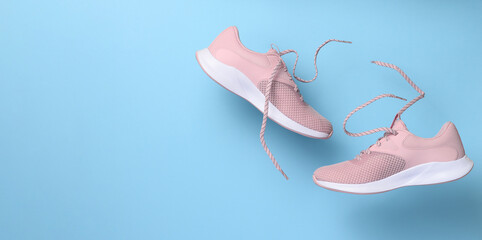 Pink women's sports sneakers with laces levitate on a blue background