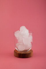 Ice cubes in glass cup on pink background. Serving set for your ice tea or other refreshing summer drinks.