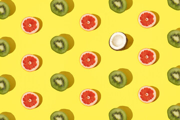 Arranged kiwi, grapefruit and coconut on a minimal yellow background.