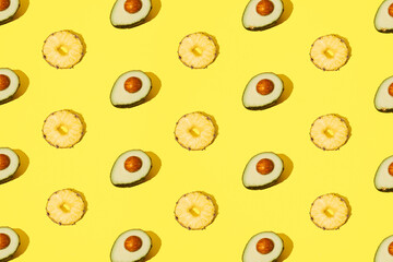 Avocado and pineapple arranged on a yellow background. Minima pattern and design.