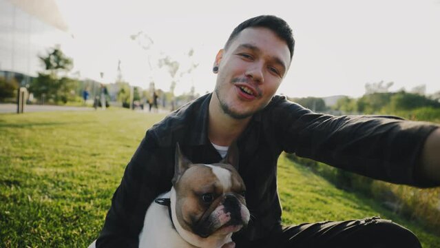 POV of Handsome Man Sitting with His Lovely Brooklyn Bulldog and Making Video Call to His Friends, Showing Pet. Guy Recording Video for Blog. Male Owner Pet Talks on Webcam