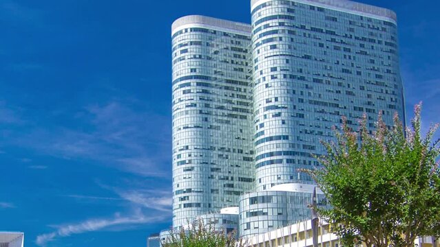 Skyscrapers and towers of La Defense timelapse hyperlapse - Modern business and residential area in the near suburbs of Paris, France. Blue cloudy sky at sunny summer day.