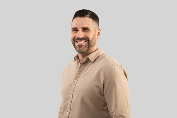 Successful middle aged male entrepreneur in shirt, looking and smiling at camera, standing over light grey background