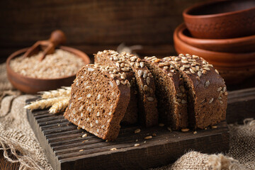 Sliced dark rye bread with sunflower seeds on a wooden board, rustic style. Healthy rye bread