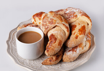 croissants and a cup of coffee on a white antique plate