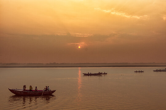 Peaceful sunrise, sunset warm landscape of river with people on the boats. Ganga river bank. Varanasi, India.