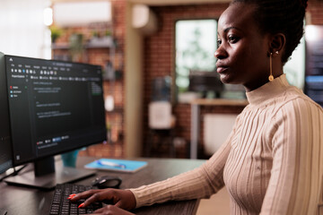 African american programmer typing big data code on computer, sitting at desk developing program using html script. Tech enginner writing ai algorithm working in it programming agency