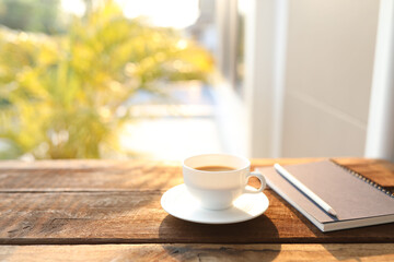 Coffee cup and notebook and pencil on wooden table