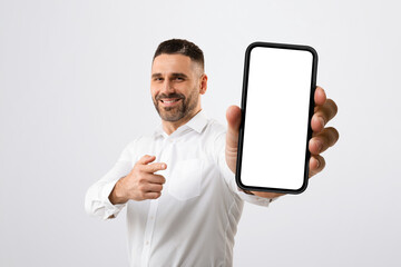 Positive male entrepreneur pointing at giant blank smartphone screen, recommending new mobile app...