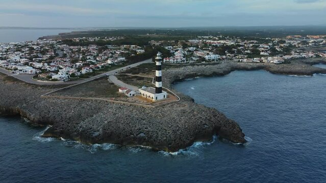 Aerial view of small village along the coast of Spain with lighthouse in the foreground.