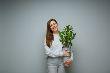 Smiling woman holding home plant in pot.