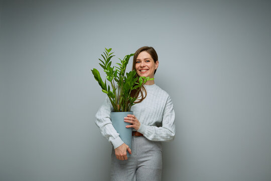 Smiling woman holding home plant in pot.