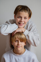 Two happy boys, happy brothers who are seriosly happily together. Brothers stay on grey background. modern tenagers.book cover. one boy in focus other out of focus