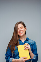 Fototapeta premium Smiling woman student in blue shirt holding yellow book.