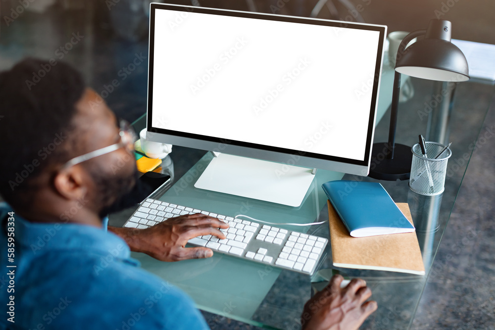 Wall mural unrecognizable black businessman using computer with empty blank screen, offering space for mockup o