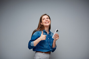 Woman using smartphone showing thumb up. Portrait of smiling girl on gray back.