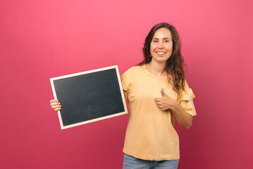 Fototapeta na wymiar Handsome young woman is holding a small blank black board and a thumb up.