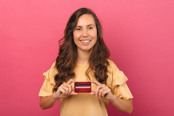 Young smiling woman is holding a plastic red credit card she has chosen.