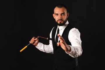 Young serious bearded strong man wearing suit and tie is using his nunchaku.