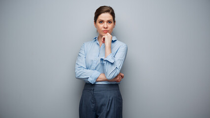 Portrait of serious thinking business woman on gray background.