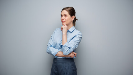 Portrait of serious thinking business woman on gray background looking away.