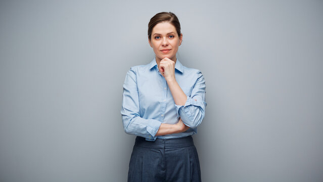 Portrait of serious thinking business woman on gray background.